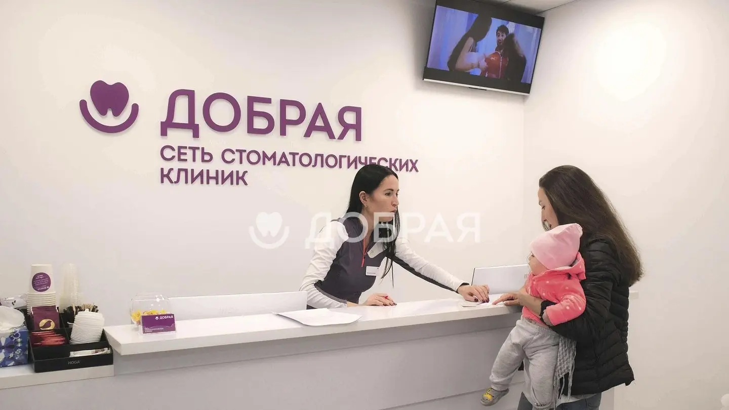 Мама с ребёнком на руках у стойки администратора клиники «Добрая»